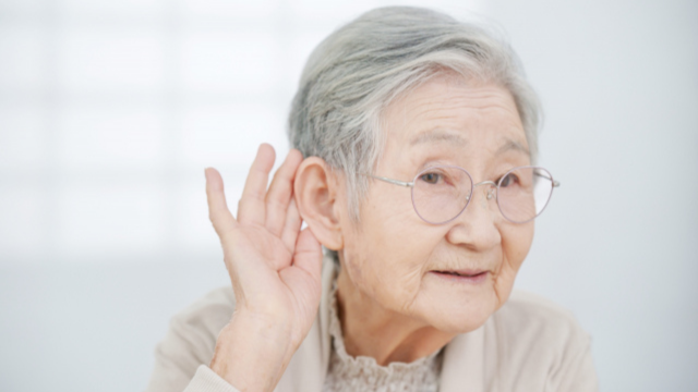 耳に手をかざしている高齢女性