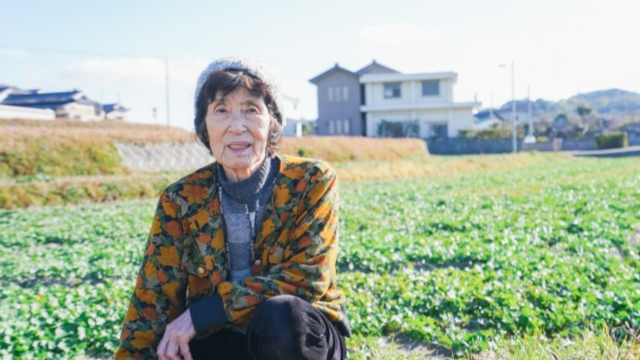 畑に座っている高齢女性